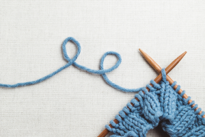 Tricot bleu et 2 aiguilles à tricoter